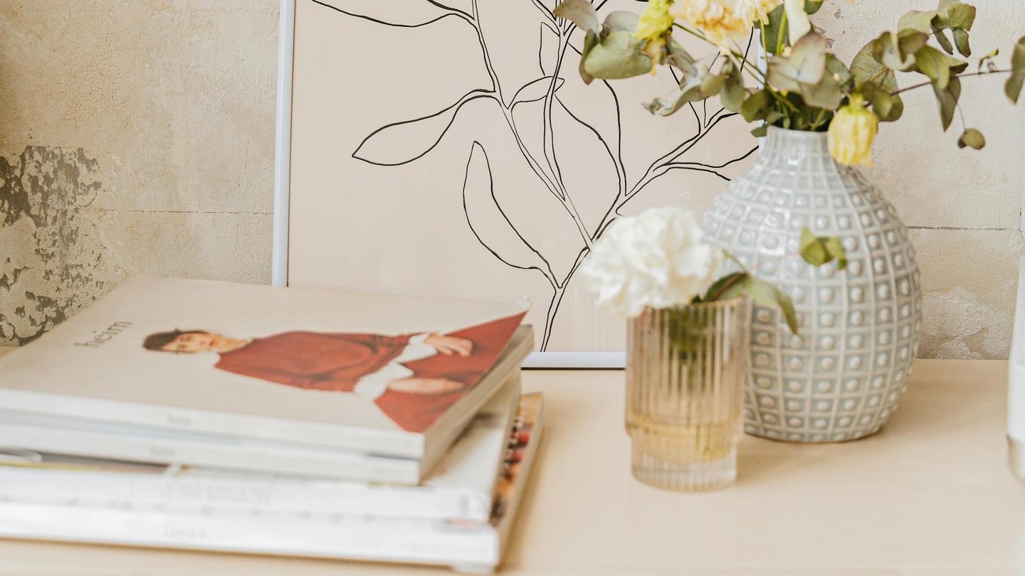Das Foto zeigt Coffee Table Books auf einer Kommode neben zwei Blumenvasen.